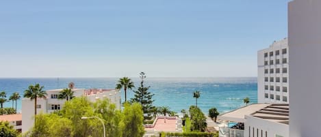 A coastal hotel with a view of the sea, surrounded by greenery and modern architecture.