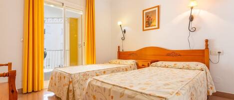 A hotel room with two beds, a wooden headboard, a painting on the wall, and a window with yellow curtains.
