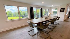 A spacious room with a large wooden table and six metal chairs, large windows with curtains, and a view of a green landscape. - 9FR Renovated home with beautiful views, large yard, dogs welcome! AC (Bethlehem)