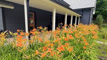 A house with a porch and a garden of orange lilies.