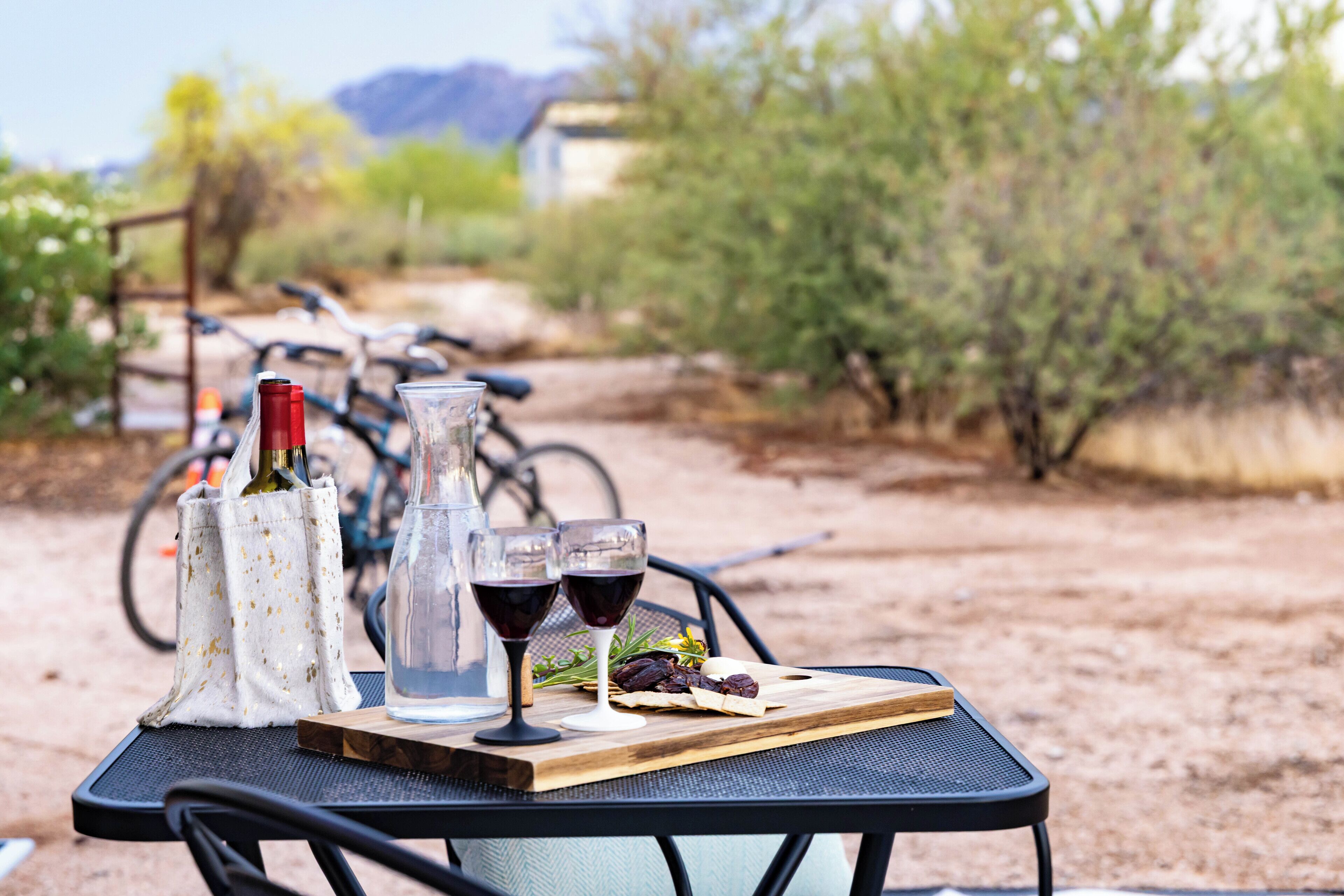 An outdoor dining setup with a table, chairs, and a bottle of wine.