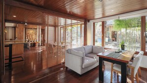 A modern interior with a wooden ceiling, a sofa, a dining table, and a view of the outdoors. - Yulong Sadhu Inn (Lijiang)