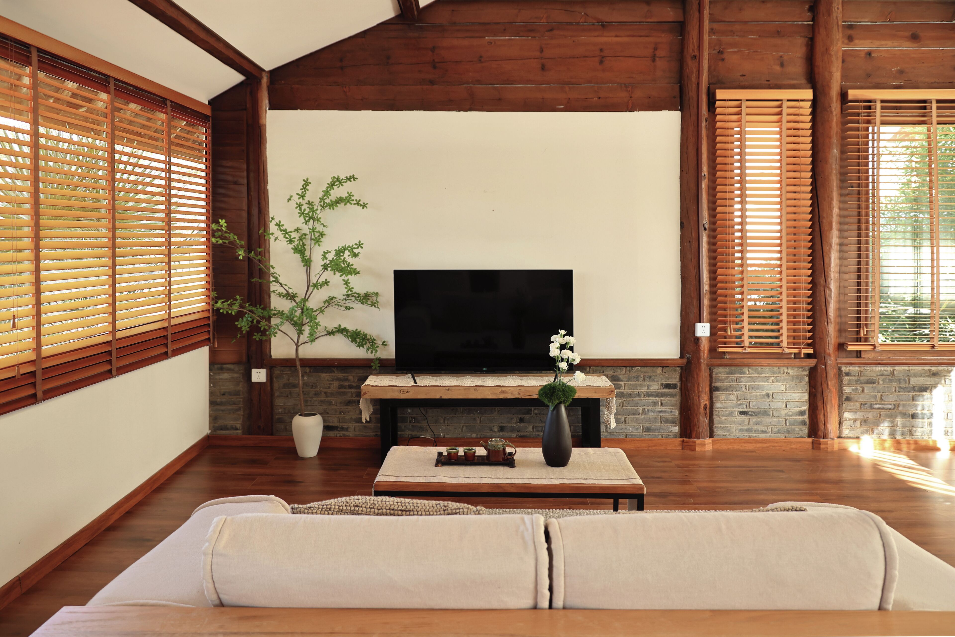 A living room with a TV, wooden blinds, a sofa, and a fireplace.