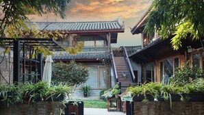 A traditional building with a tiled roof, a wooden staircase, and a brick wall. - Yulong Sadhu Inn (Lijiang)
