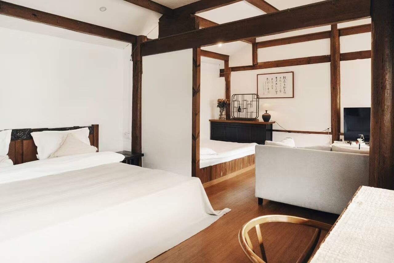 A hotel room with a large bed, a sofa, a desk, and a TV.