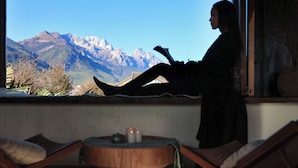 A person reading by a window with a mountain view. - Yulong Sadhu Inn (Lijiang)