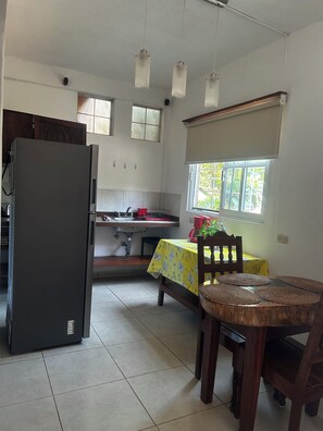 A kitchen with a refrigerator, sink, and dining table with chairs.