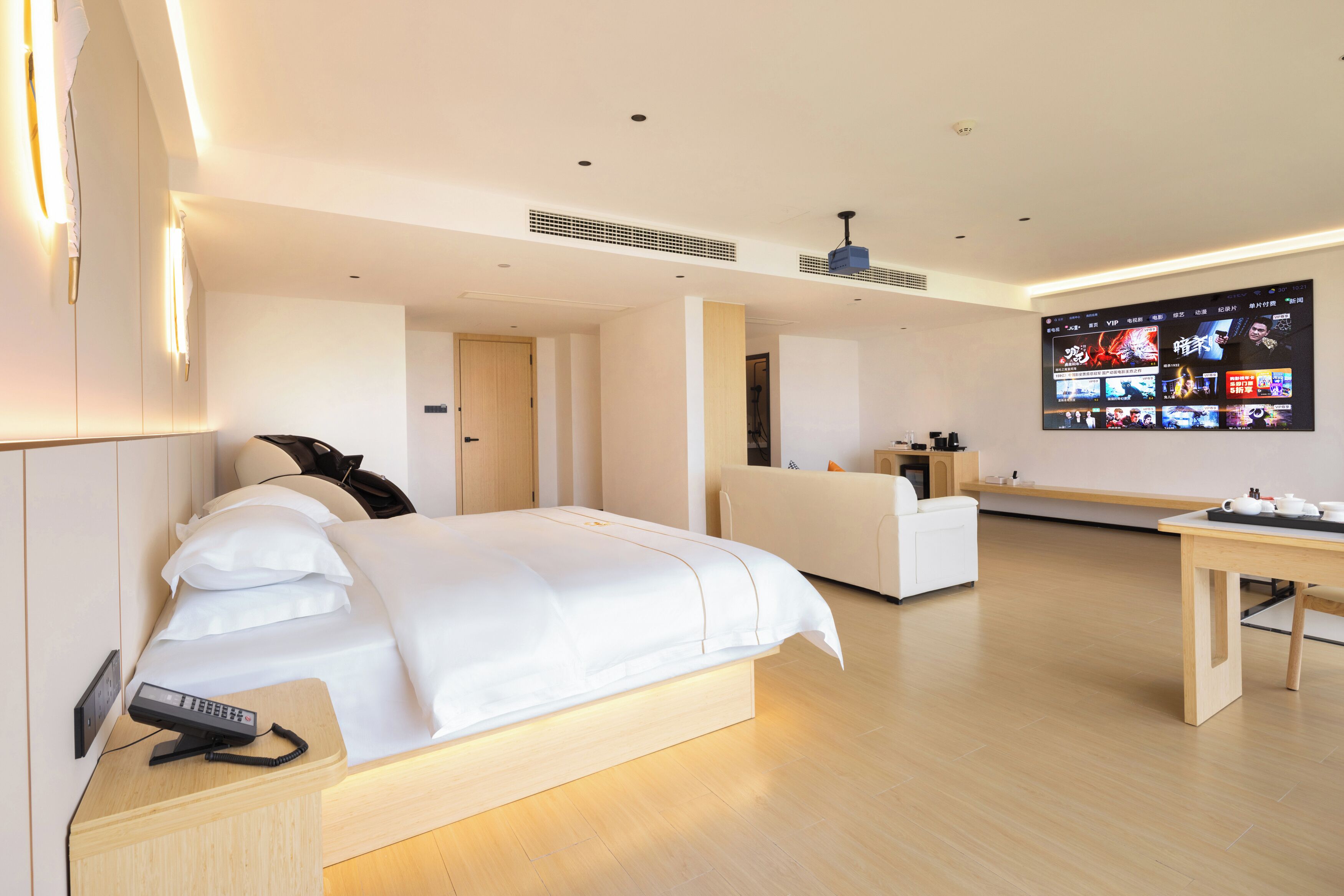 A modern hotel room with a large bed, a desk, a flat-screen TV, and a sofa.