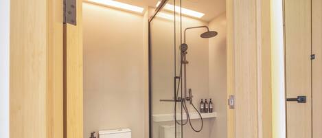 A modern bathroom with a glass-enclosed shower, a white toilet, and a tiled floor.