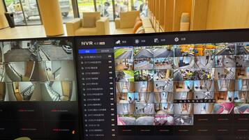 Un écran de surveillance à double affichage présentant les images de plusieurs caméras de sécurité, filmant le hall d’un hôtel et ses environs.
