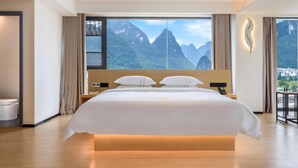 A modern hotel room with a large bed, a view of mountains, and a wooden floor. - Mountain Search Snow View Hotel (Guilin)
