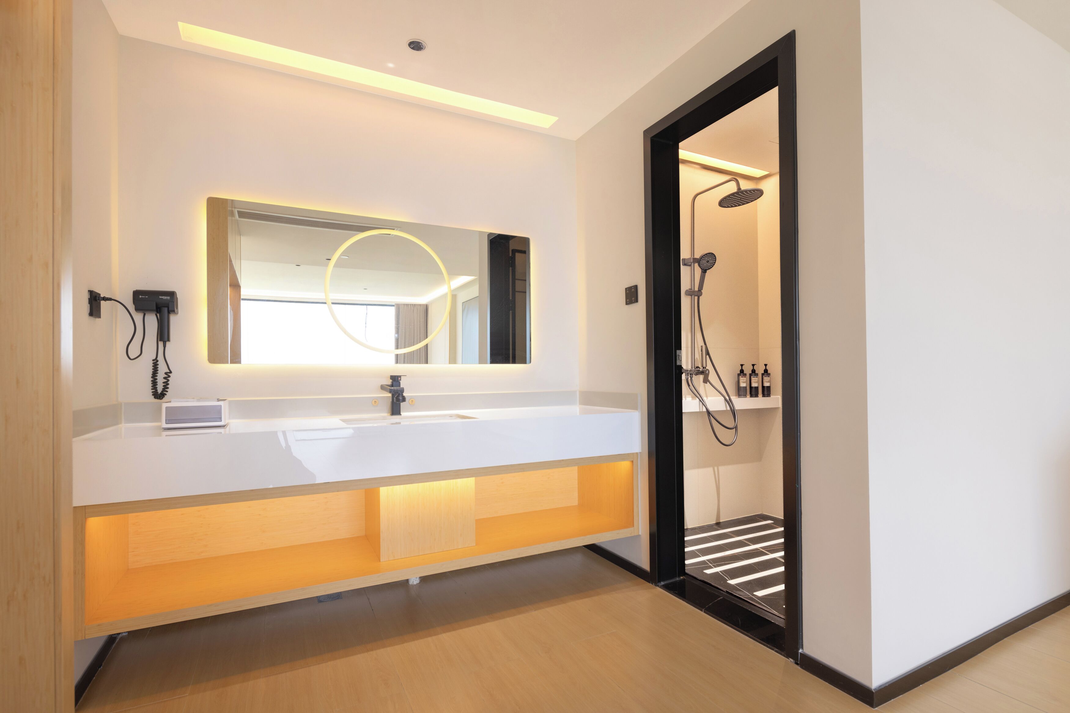 Un baño moderno con tocador blanco, un espejo grande y una zona de ducha.