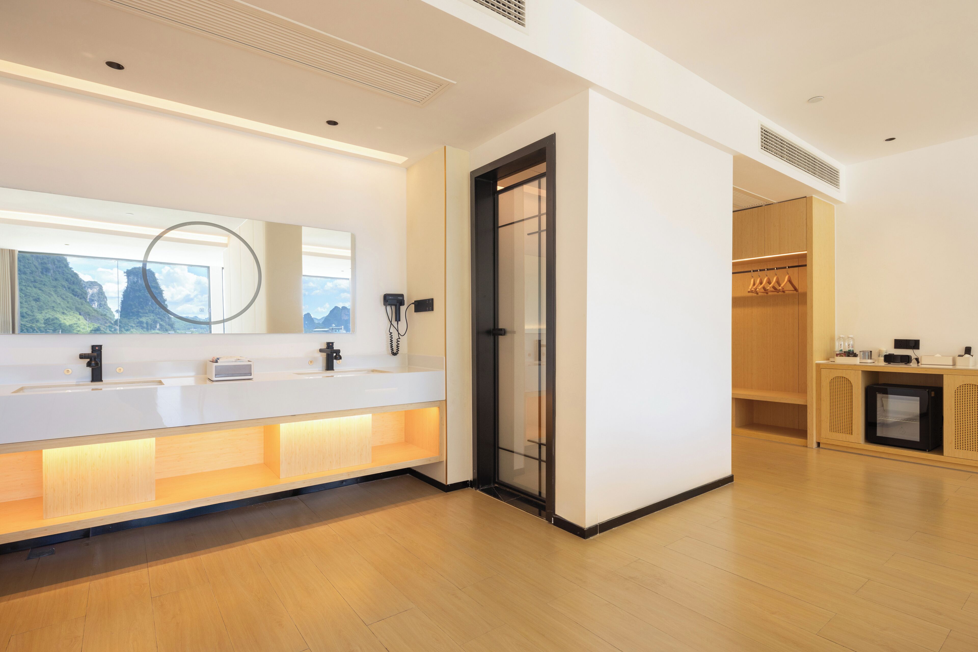 A modern bathroom with a large mirror, two sinks, and a shower area.