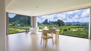 A spacious room with a large window offering a view of a mountainous landscape. - Mountain Search Snow View Hotel (Guilin)