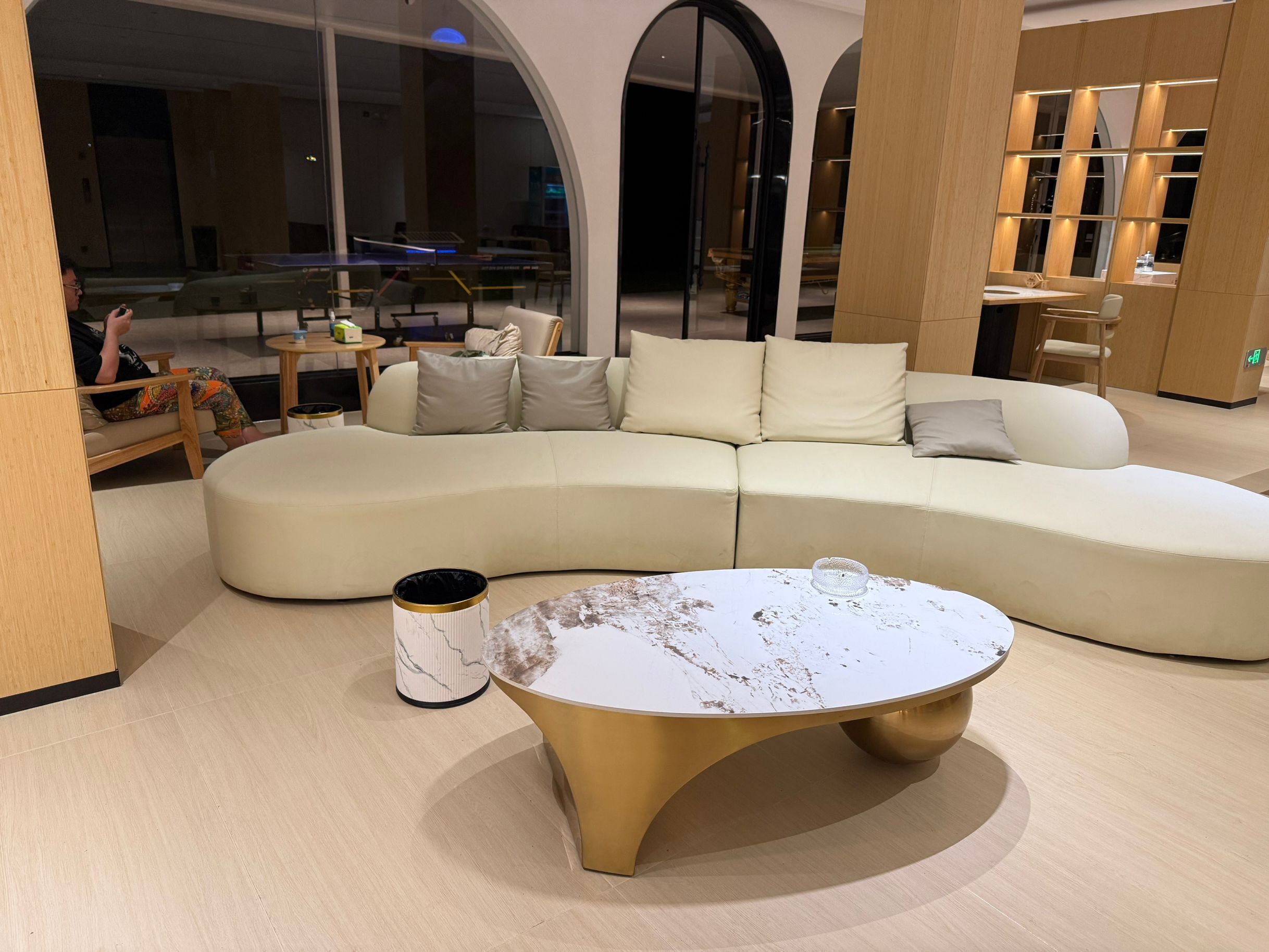 A modern living room with a curved sectional sofa, a marble coffee table, and a small side table.