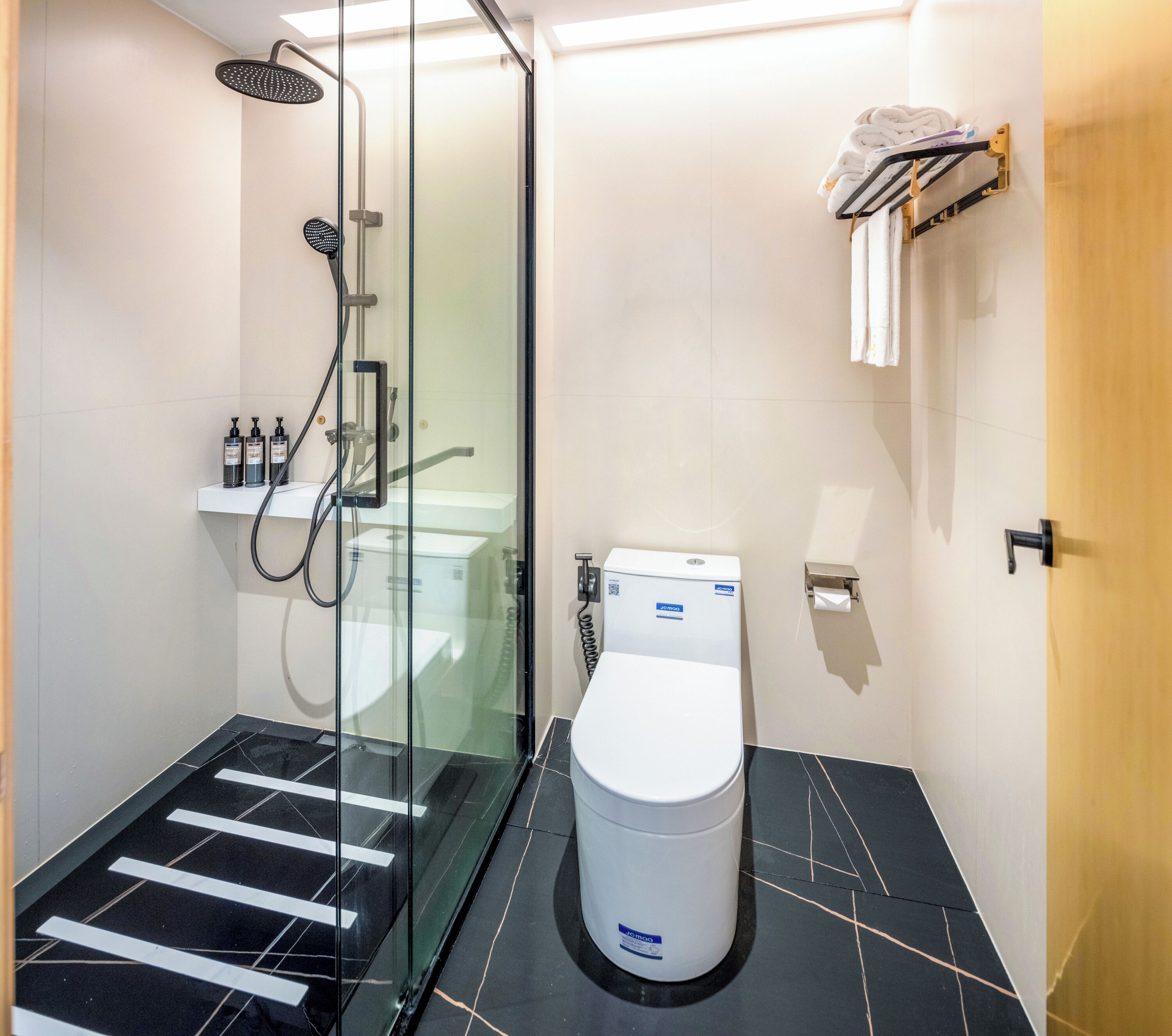 A modern bathroom with a glass shower enclosure, a toilet, and a towel rack.