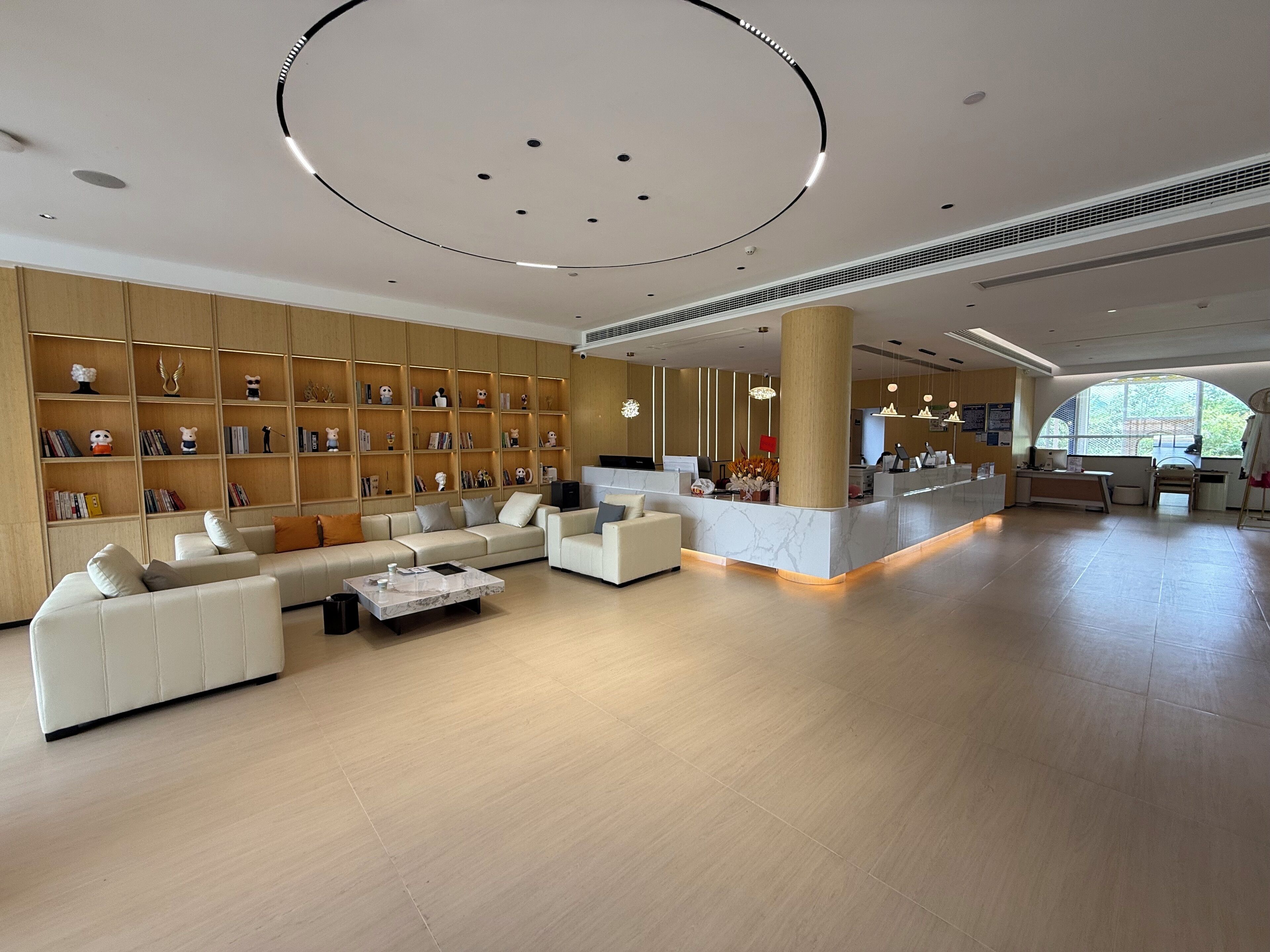 A spacious lobby with a reception desk, seating area, and bookshelves.