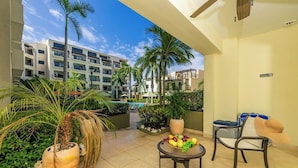 Ein Hotelbalkon mit Pool, Palmen und Obstschale.