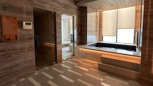Un baño moderno con una bañera grande, paredes de madera y piso de baldosas.