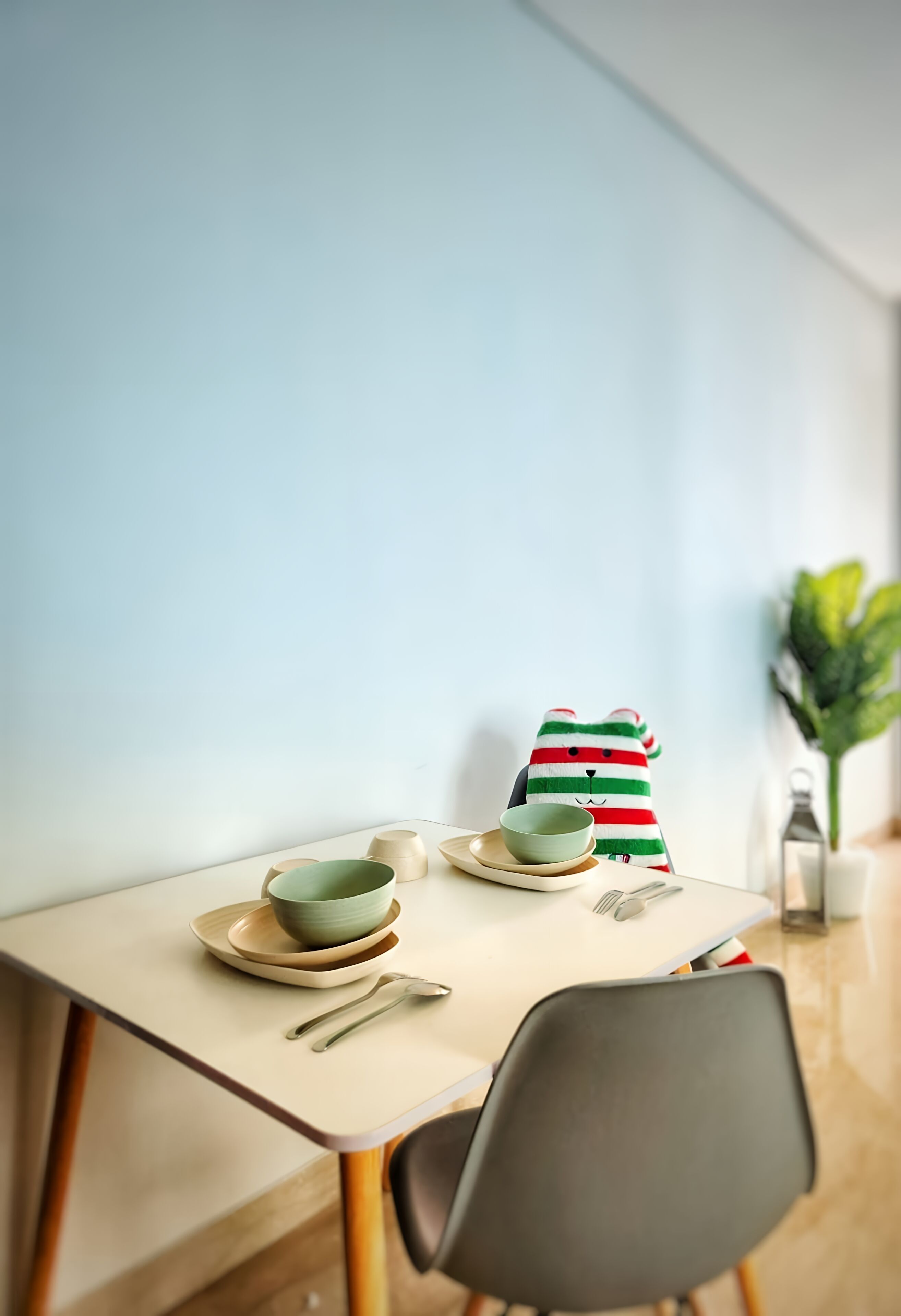 A dining table with a green bowl, a striped cloth, and a spoon.