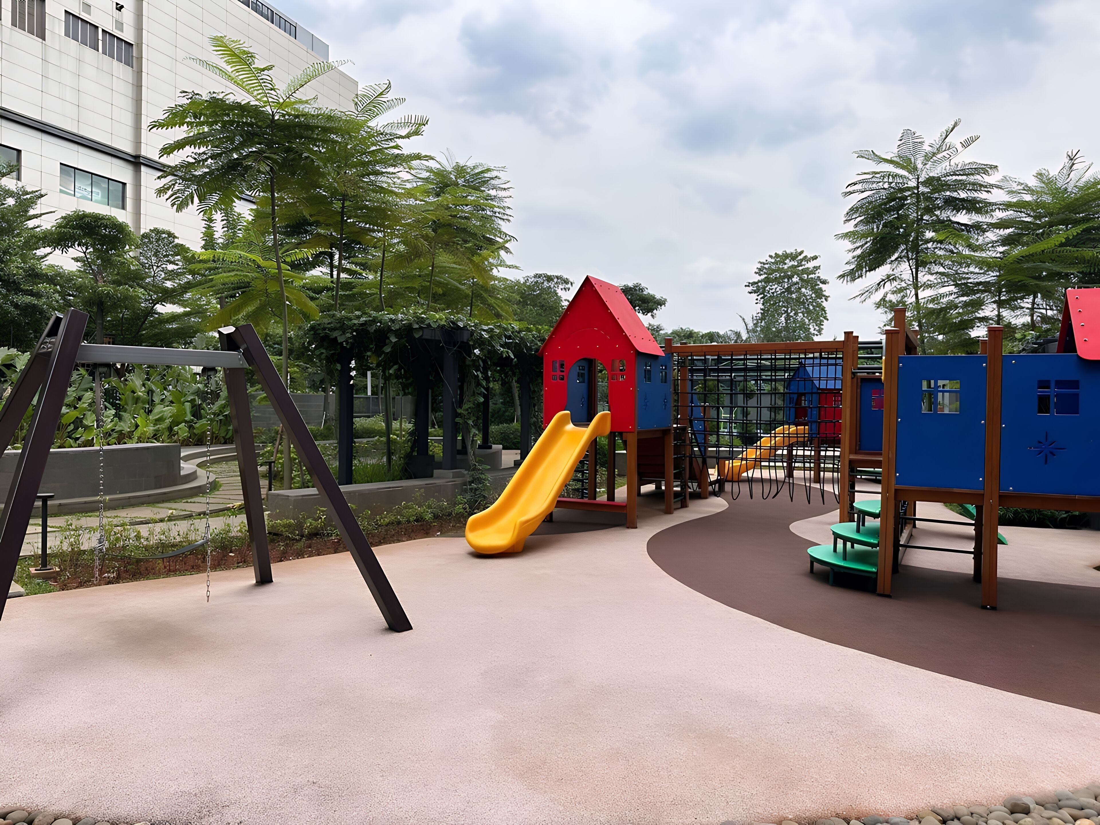 Une aire de jeux avec un toboggan, des balançoires et des structures d’escalade.