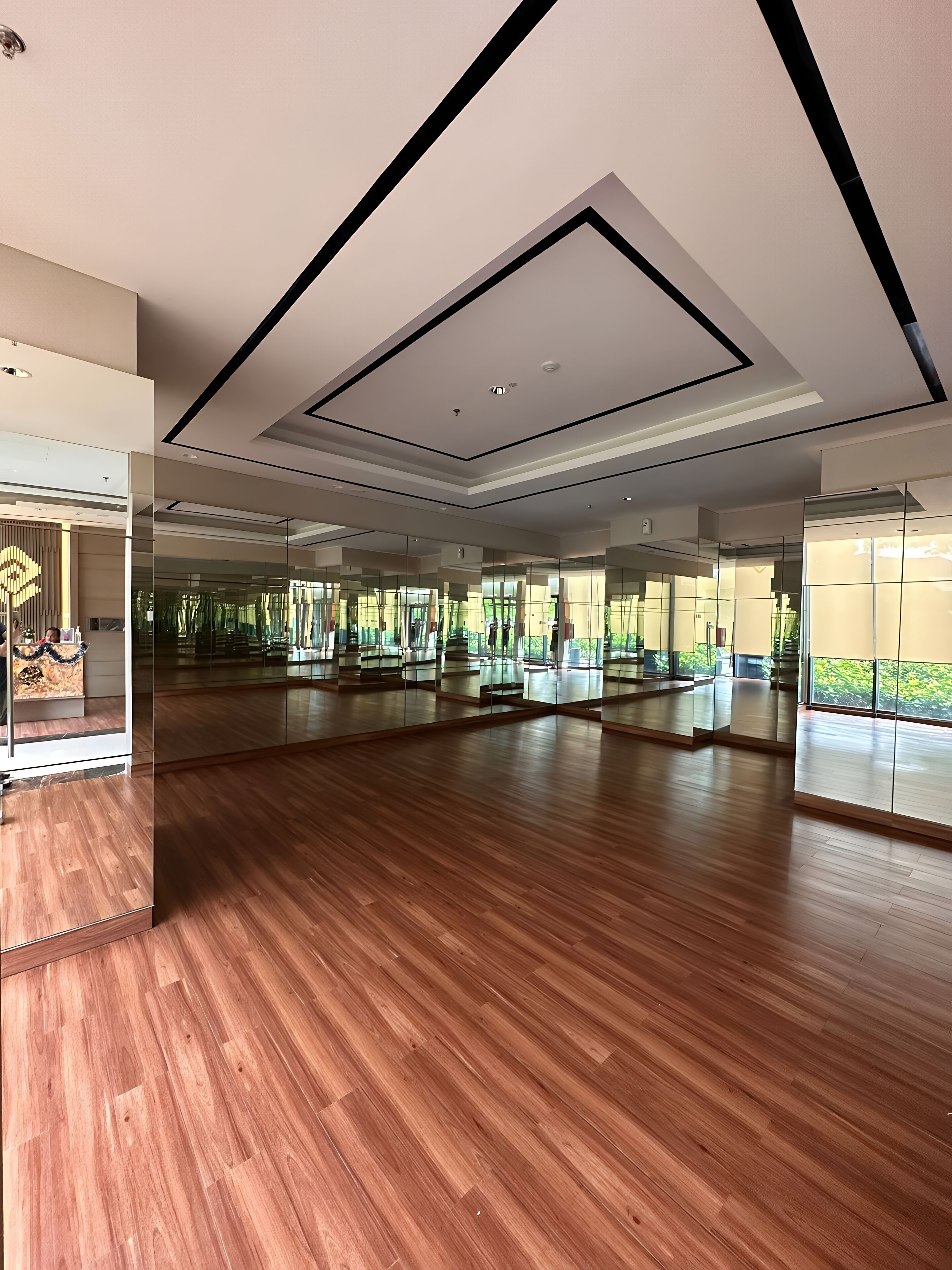 Une pièce spacieuse dotée d’un plancher en bois, de grands miroirs et d’un design moderne au niveau du plafond.