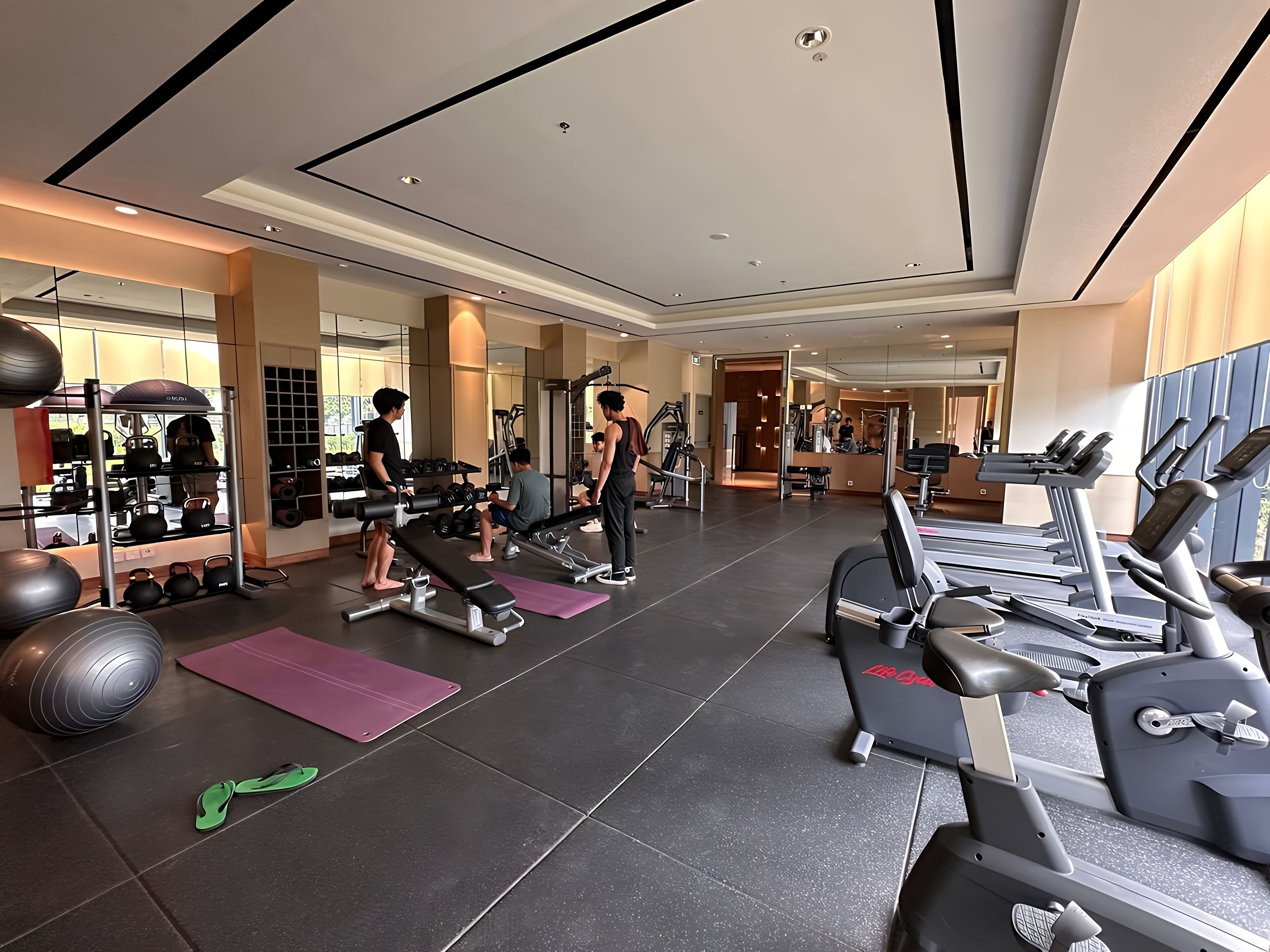 Un gimnasio con cintas de correr, máquinas de pesas y pelotas de ejercicio.