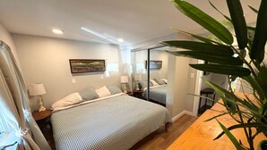 Een slaapkamer met een bed, nachtkastjes, een spiegel en een potplant.