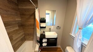 Een moderne badkamer met een houten wand, een wit ligbad, een wastafel en een toilet.