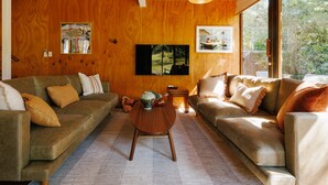 A cozy living room with two sofas, a coffee table, and a TV mounted on the wall.
