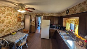 Une cuisine dotée de meubles en bois, d’un réfrigérateur, d’un four à micro-ondes et d’un coin repas avec une table et des chaises.