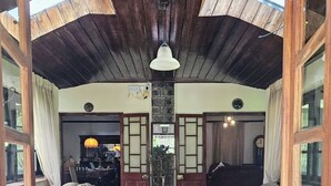A cozy interior with wooden beams, a central seating area with sofas, and a stone wall.