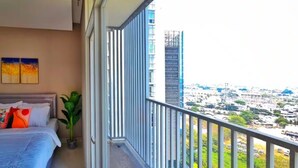 Ein Balkon mit Blick auf die Stadt, ein Bett mit Kissen und eine Pflanze.