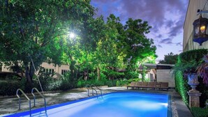 A swimming pool with steps, surrounded by lush greenery and trees.