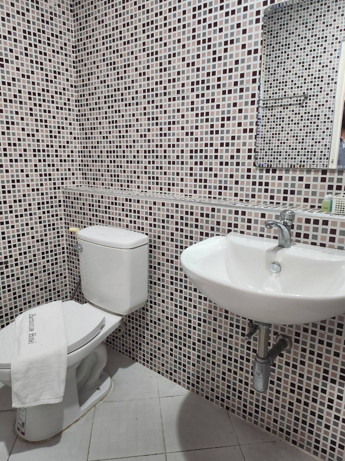 A bathroom with a toilet, sink, and tiled walls.