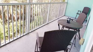 Ein Balkon mit Tisch und zwei Stühlen mit Blick auf einen Garten mit verschiedenen Pflanzen.