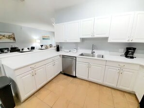 A modern kitchen with white cabinets, a dishwasher, and a coffee maker. - Cozy 3-bedroom condo very close to Disney (Kissimmee)