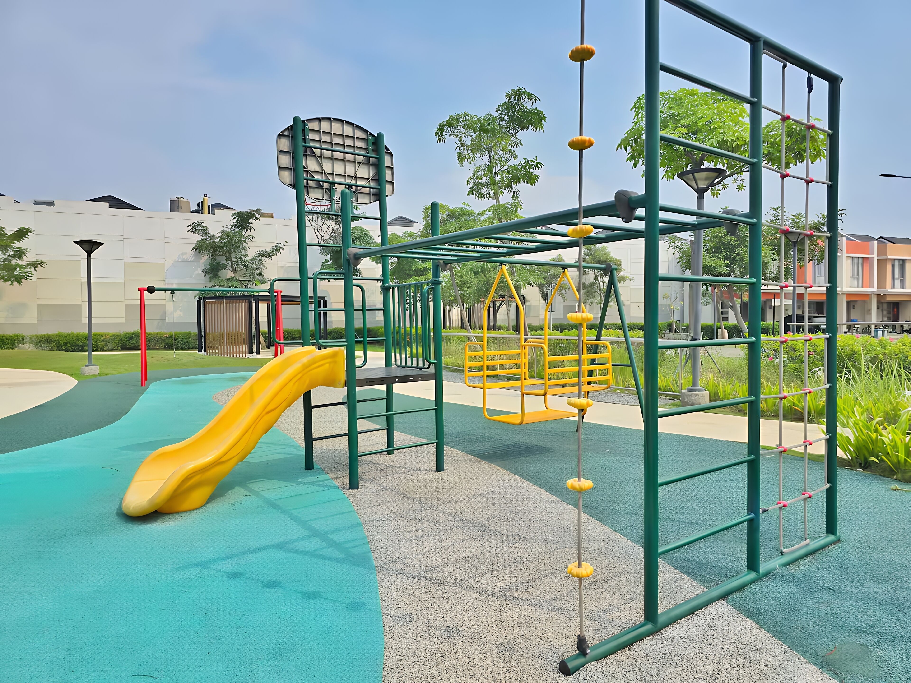 Un parque infantil con un tobogán amarillo, estructuras para escalar y un aro de baloncesto.