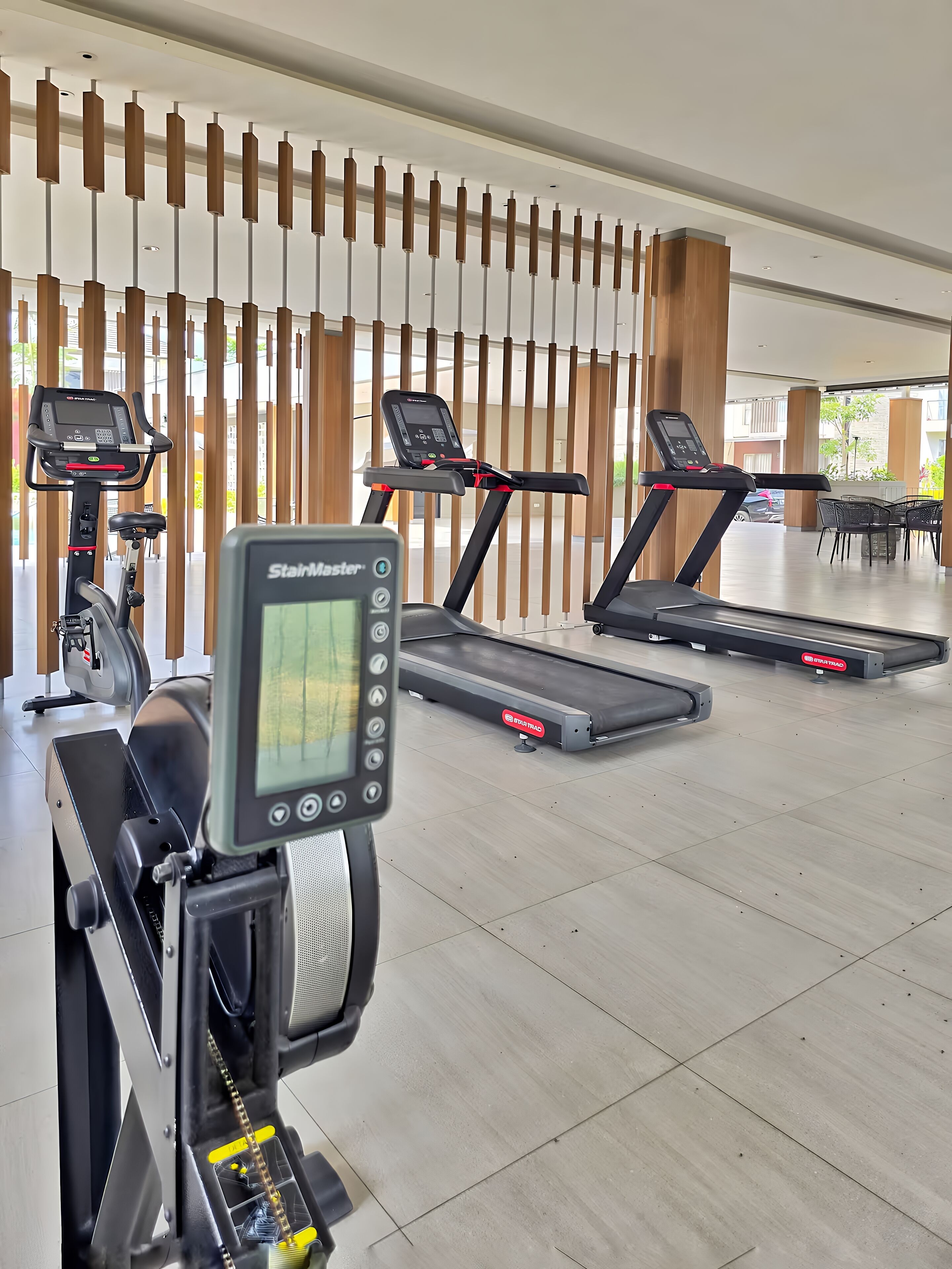 Une salle de sport équipée de tapis de course, de vélos d’appartement et d’un appareil d’escalier.
