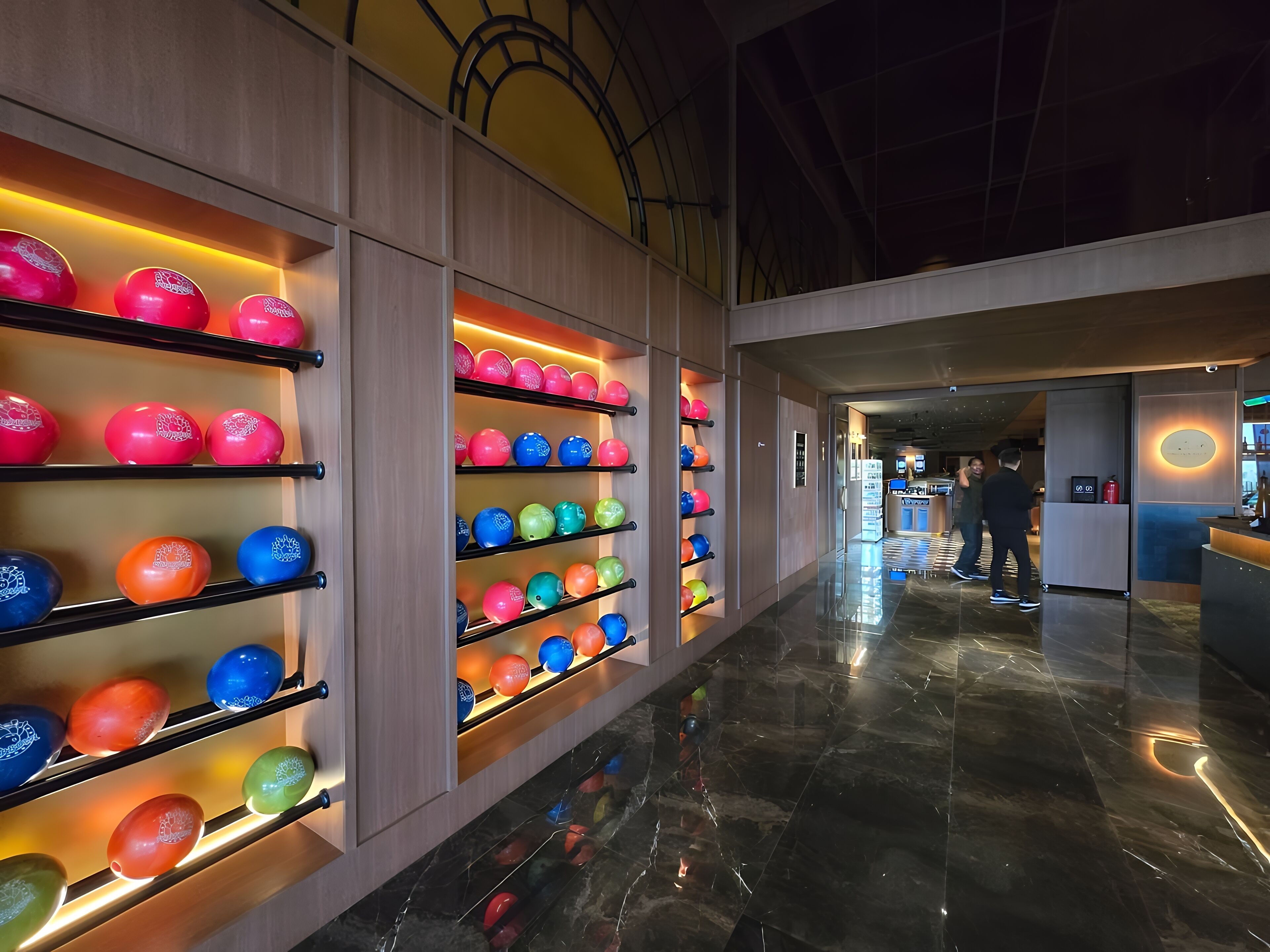 A corridor with bowling lanes and a reception area.