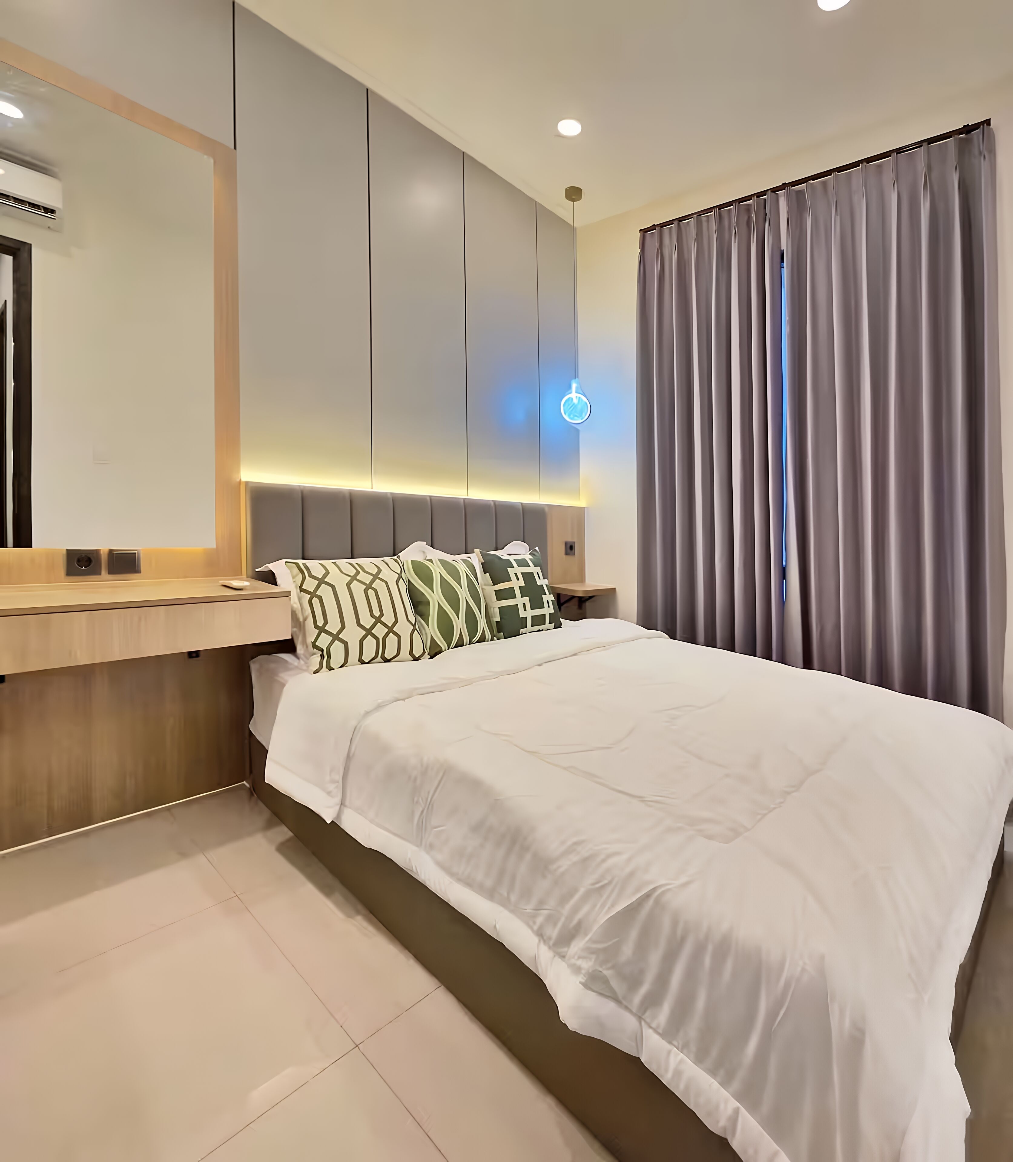Una habitación de hotel moderna con una cama grande, una mesita de noche, un espejo y una ventana con cortinas.