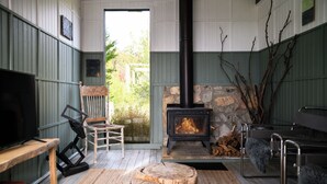 A cozy room with a stone fireplace, a television, and a wooden chair.