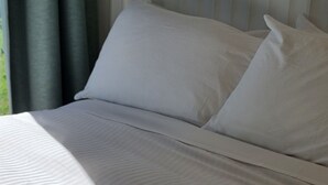 A neatly made bed with white bedding and pillows, a fluffy blanket, and a window with curtains. - The Retreat - Reconnect with nature in style (Musk)