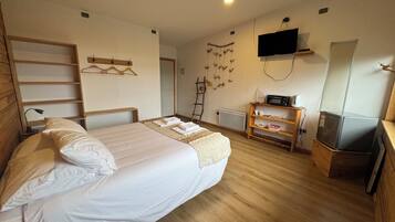 A bedroom with a bed, a wooden dresser, a television, and a mirror.