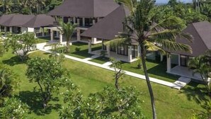 Um resort com vários edifícios, cada um com telhado escuro e rodeado por vegetação exuberante.