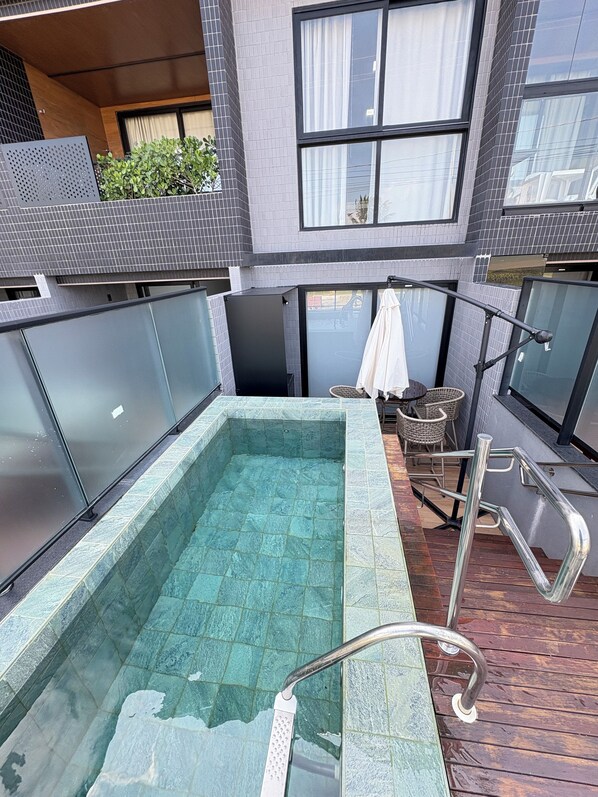 A rooftop pool with clear water, surrounded by a modern building with large windows and a covered seating area. - Melhores Flats - Luxuoso beira-mar (Cabedelo)