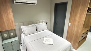 Egy modern hálószoba, amelyben található egy ágy, éjjeliszekrények, légkondicionáló és egy gardrób.