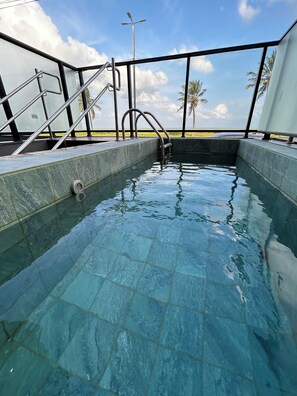 A swimming pool with a metal ladder and a view of the ocean. - Melhores Flats - Luxuoso beira-mar (Cabedelo)
