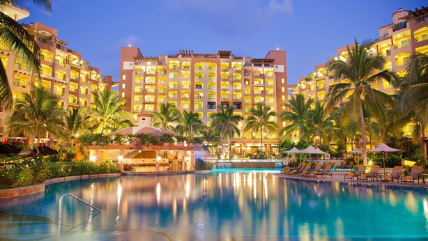 A hotel with a large pool, palm trees, and multiple balconies. - 3 BR Panoramic OF villa that sleeps 10 people, just steps from the beach and pool! (Cabo San Lucas)