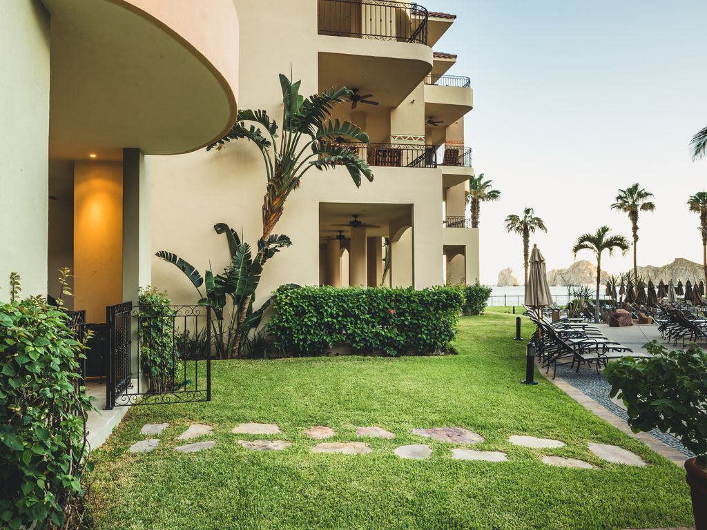 A hotel courtyard with a well-maintained lawn, palm trees, and outdoor seating area.